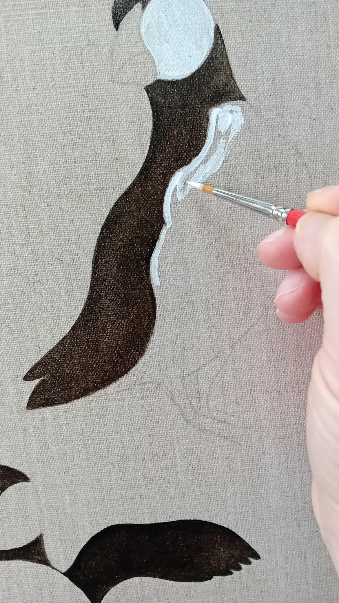 Détail du pinceau de Carine sur une toile de lin représentant un macareux
