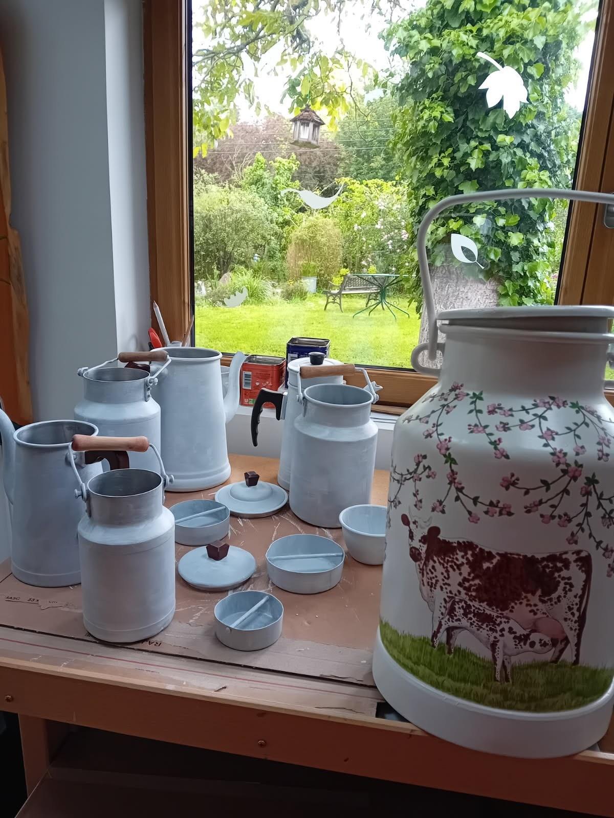 Pots à lait anciens préparés dans l'atelier, devant la fenêtre ouverte sur le jardin